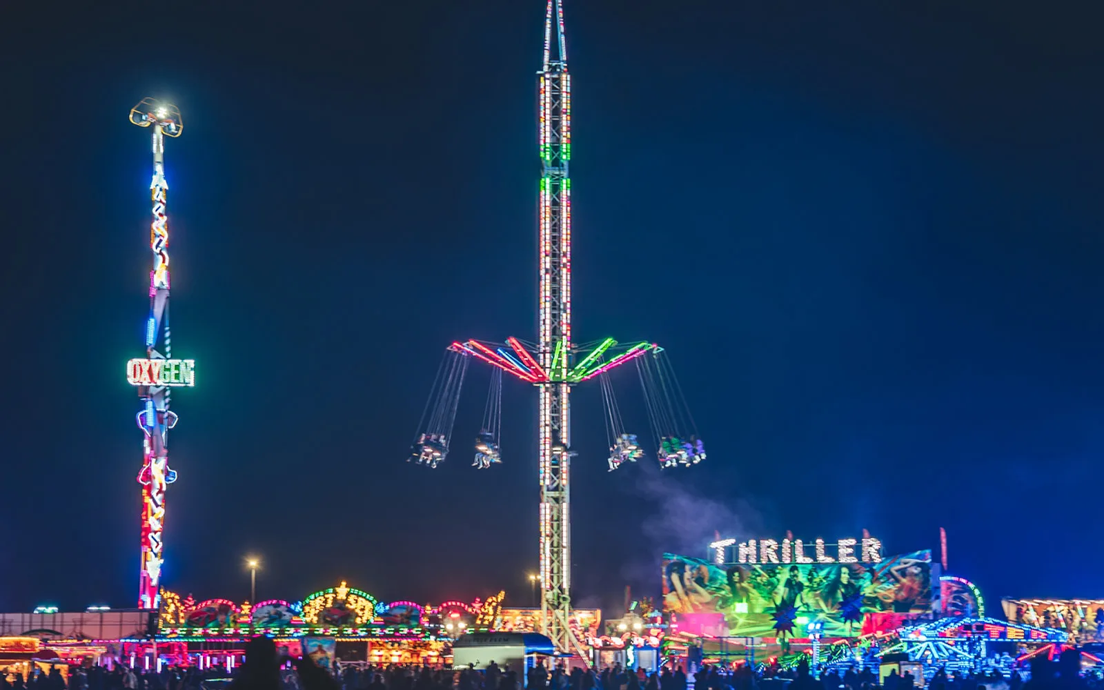 Families enjoying the illuminated fairground rides at night